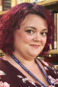 Profile of speaker Kristina Dorsett in front of library book stacks