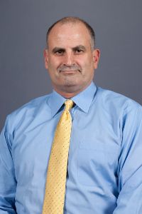 James Vike formal headshot, posed with a light blue dress shirt and gold tie.